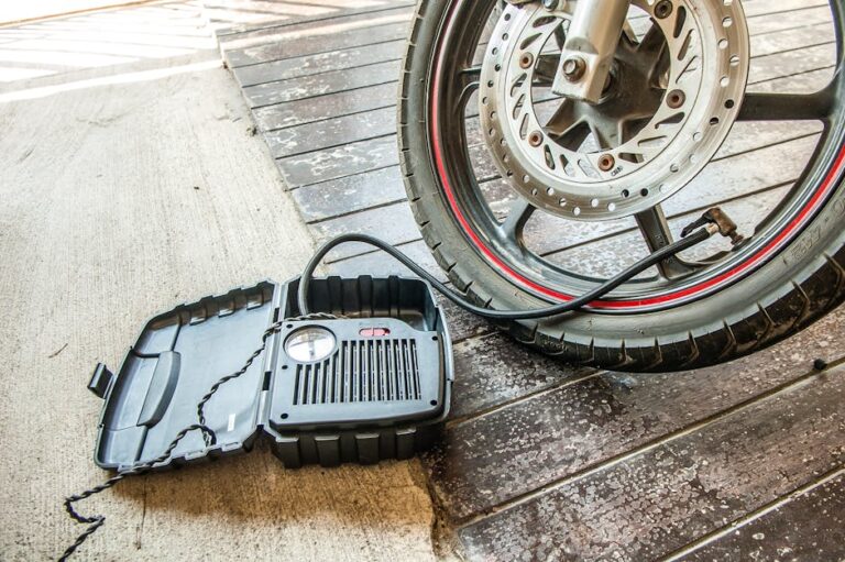Nahaufnahme eines Motorradreifens, der mit einer tragbaren Luftpumpe aufgepumpt wird.