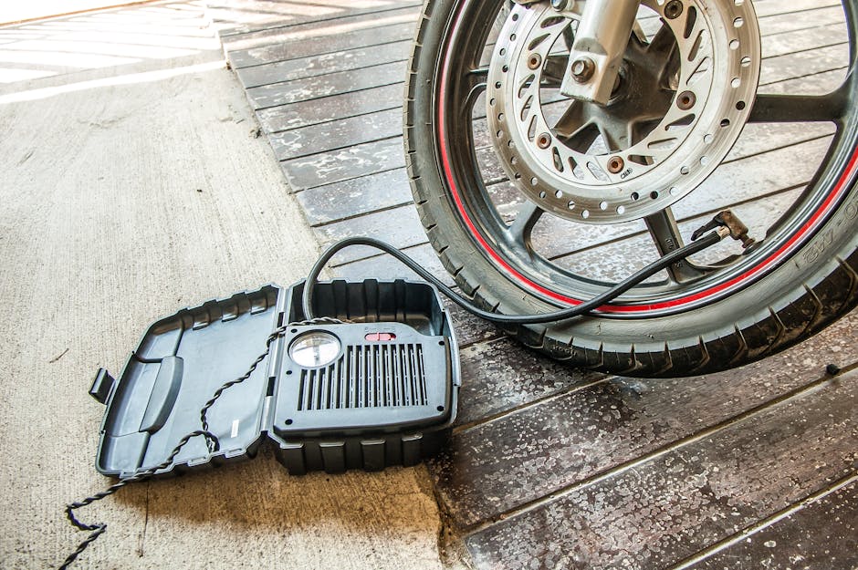 Close-up of a motorcycle tire being inflated using a portable air pump.