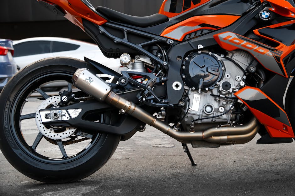 Close-up shot of an orange and black high-performance motorcycle engine in an urban setting.