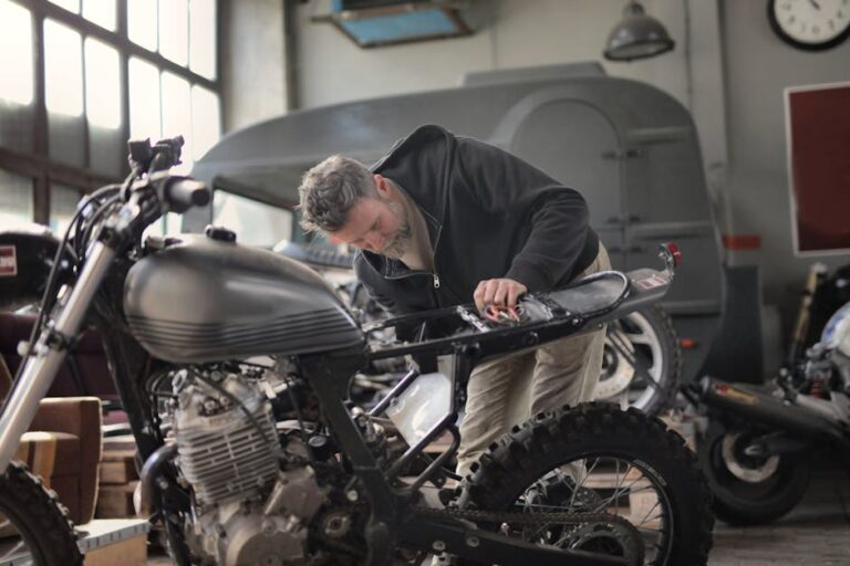 Ein erwachsener männlicher Mechaniker arbeitet in einer Werkstatt im Industrie-Stil an einem Motorrad.