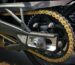 Primer plano de una cadena de moto pasando por una rueda dentada trasera