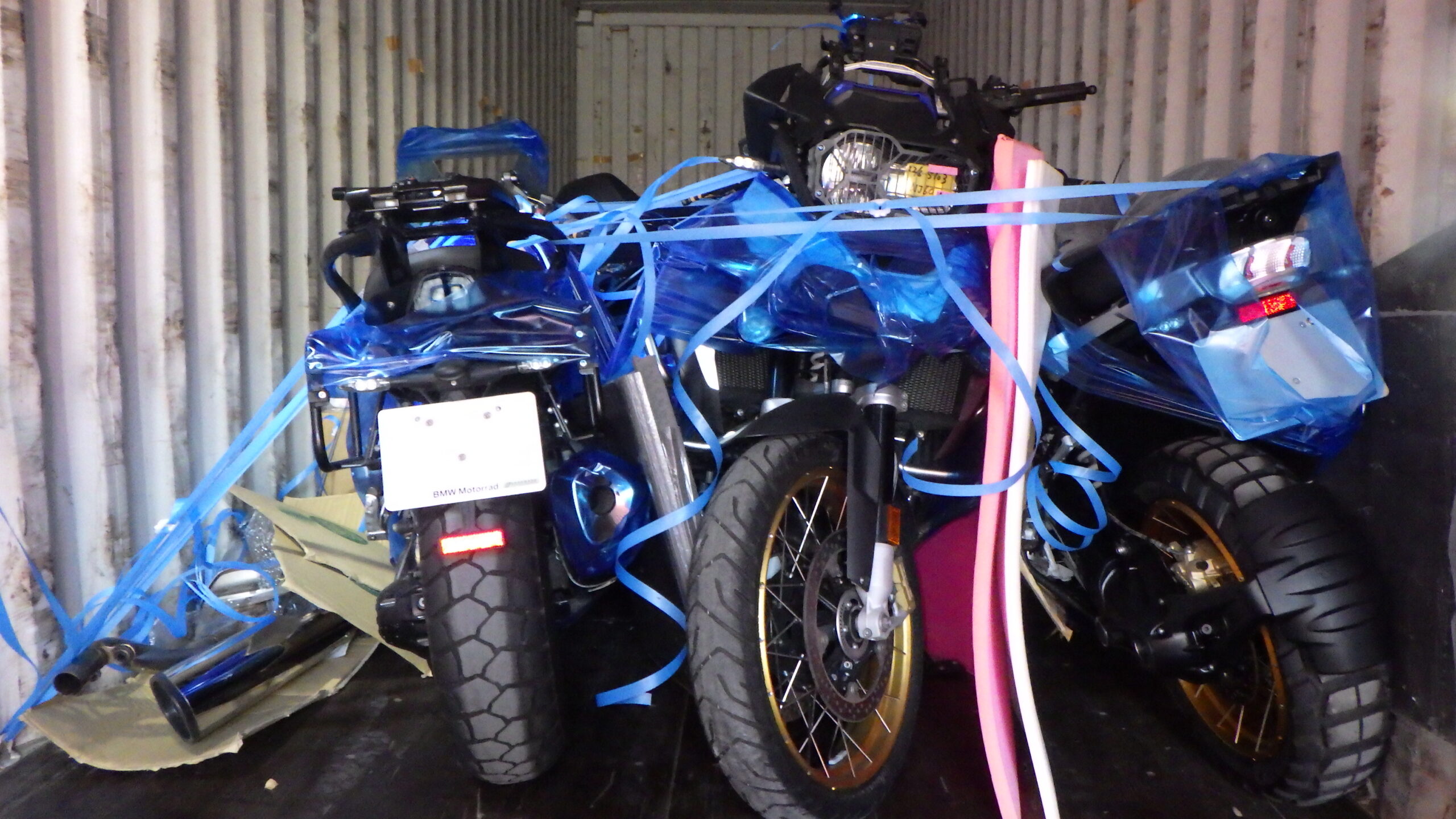 Forklift lifting a wooden crate holding a boxed motorcycle into a container