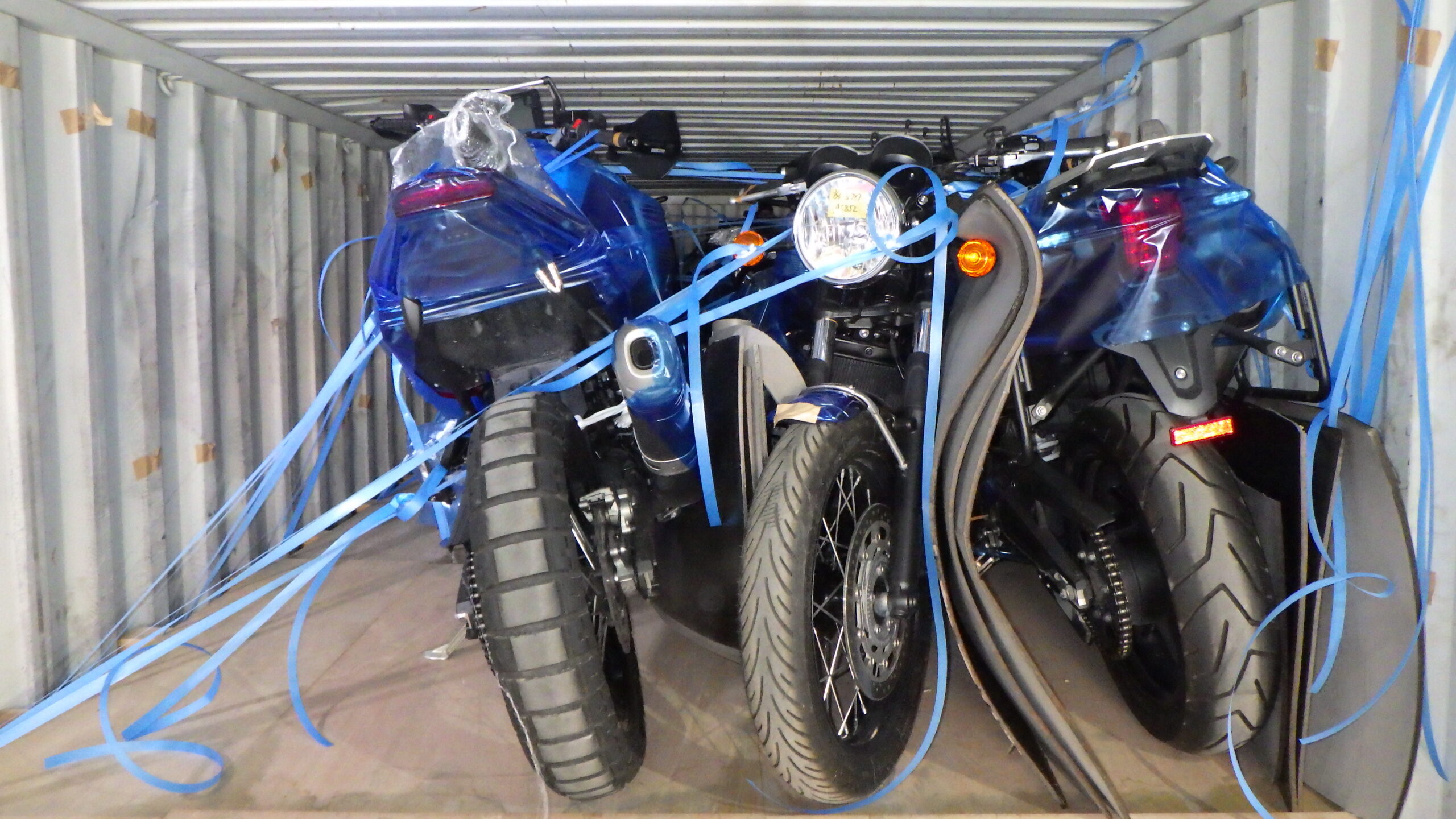 Rows of cartoned motorcycles stacked inside a loaded shipping container