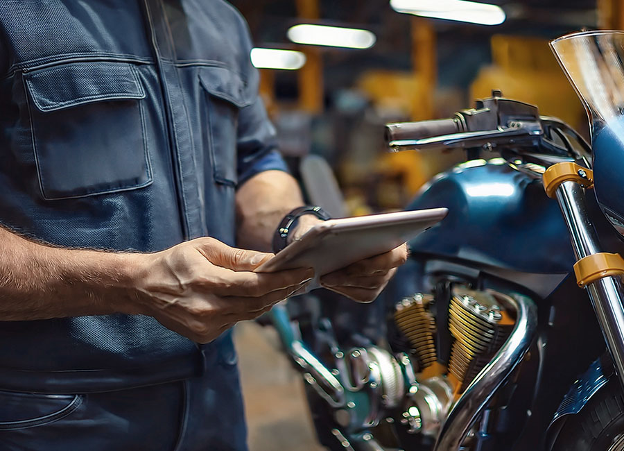 Technician inspecting a motorcycle engine during a warranty check