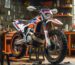 Dirt bike on a maintenance stand in a home garage with tools on the floor