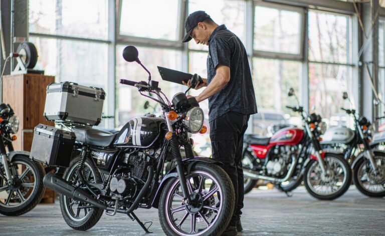 Motorcycle specification sheet with engine and chassis data on a workshop desk