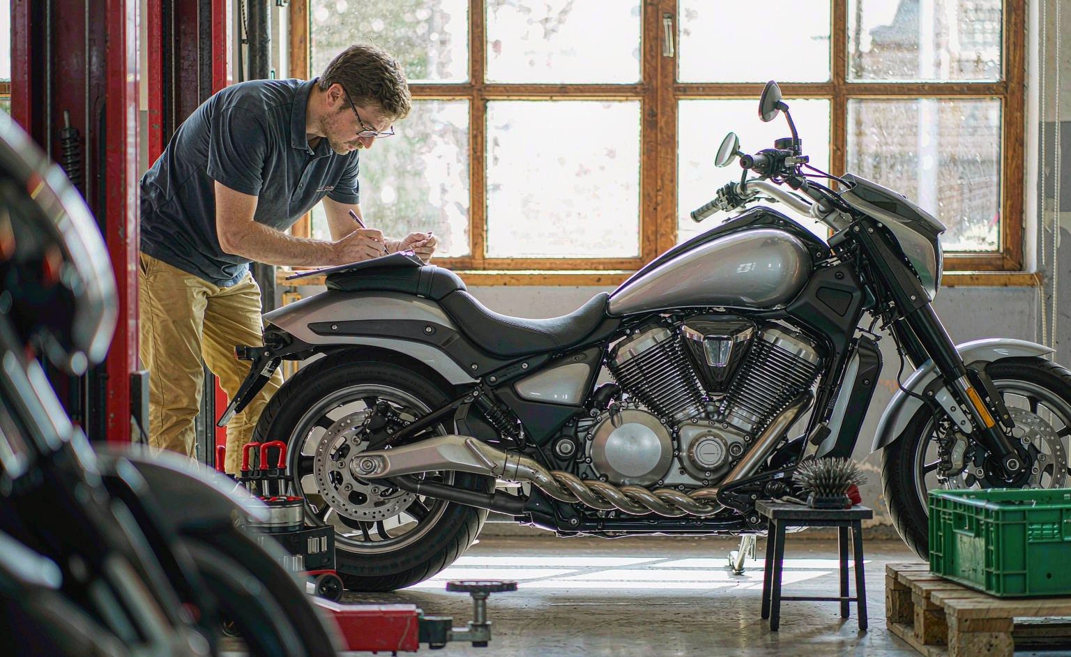 Technician performing pre-delivery inspection on a motorcycle with a checklist clipboard